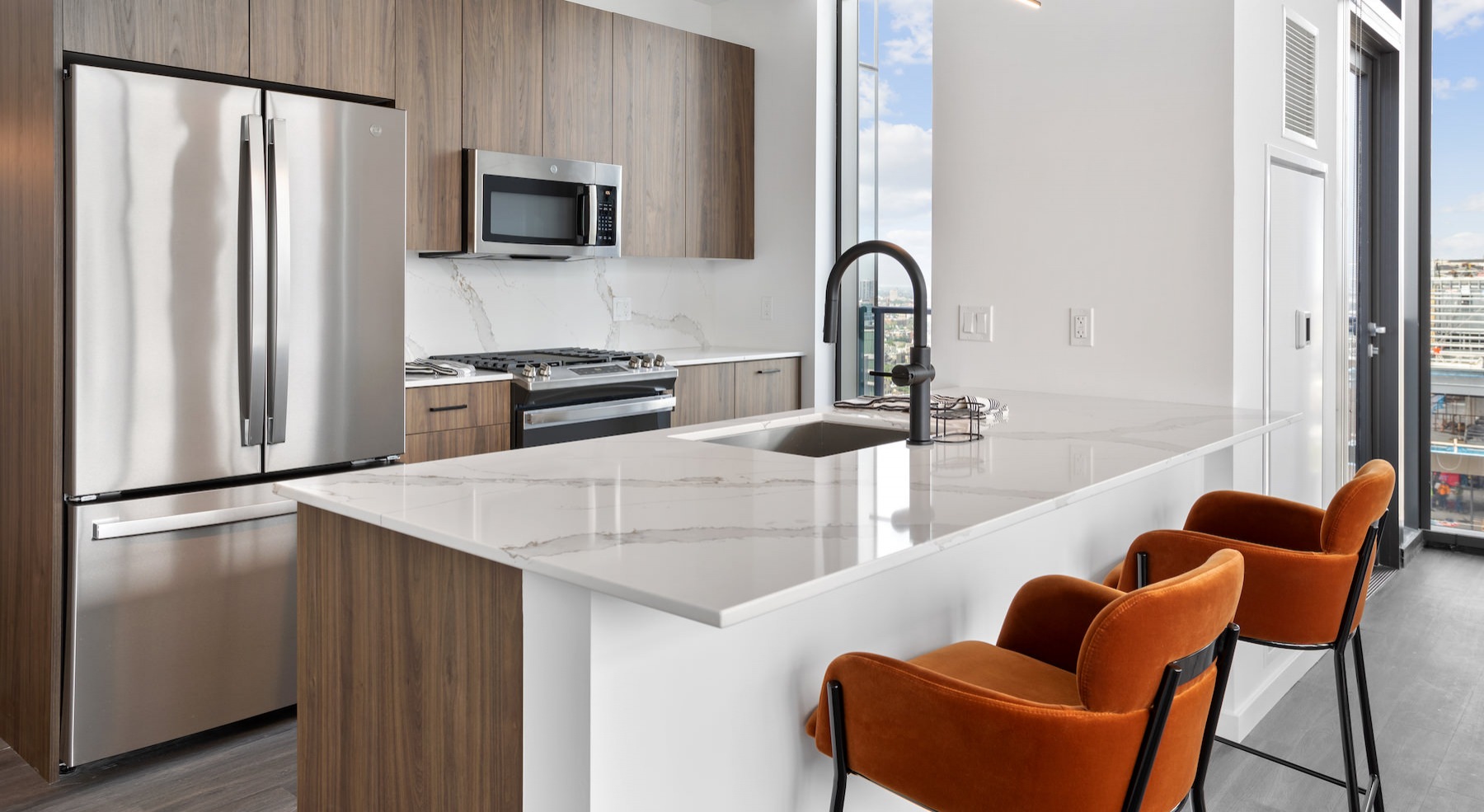 Spacious and well lit kitchen with wood floors and stainless steel appliances